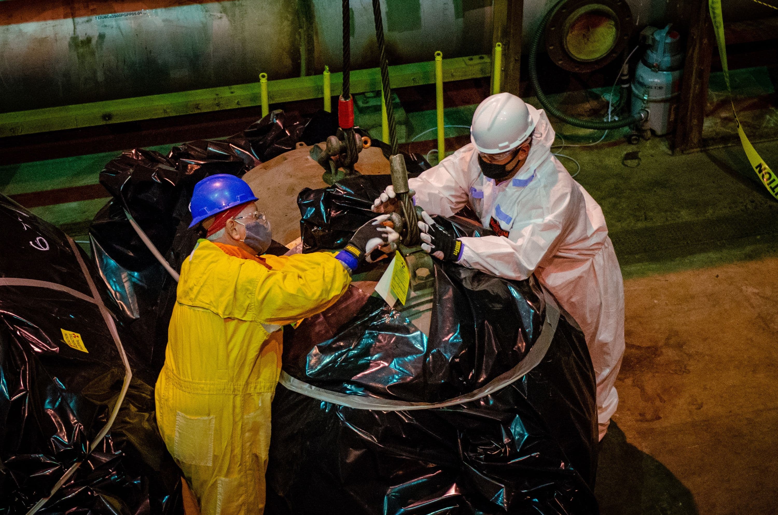 Workers rig a motor to be removed from the C-333 Process Building to make room for the material sizing area.