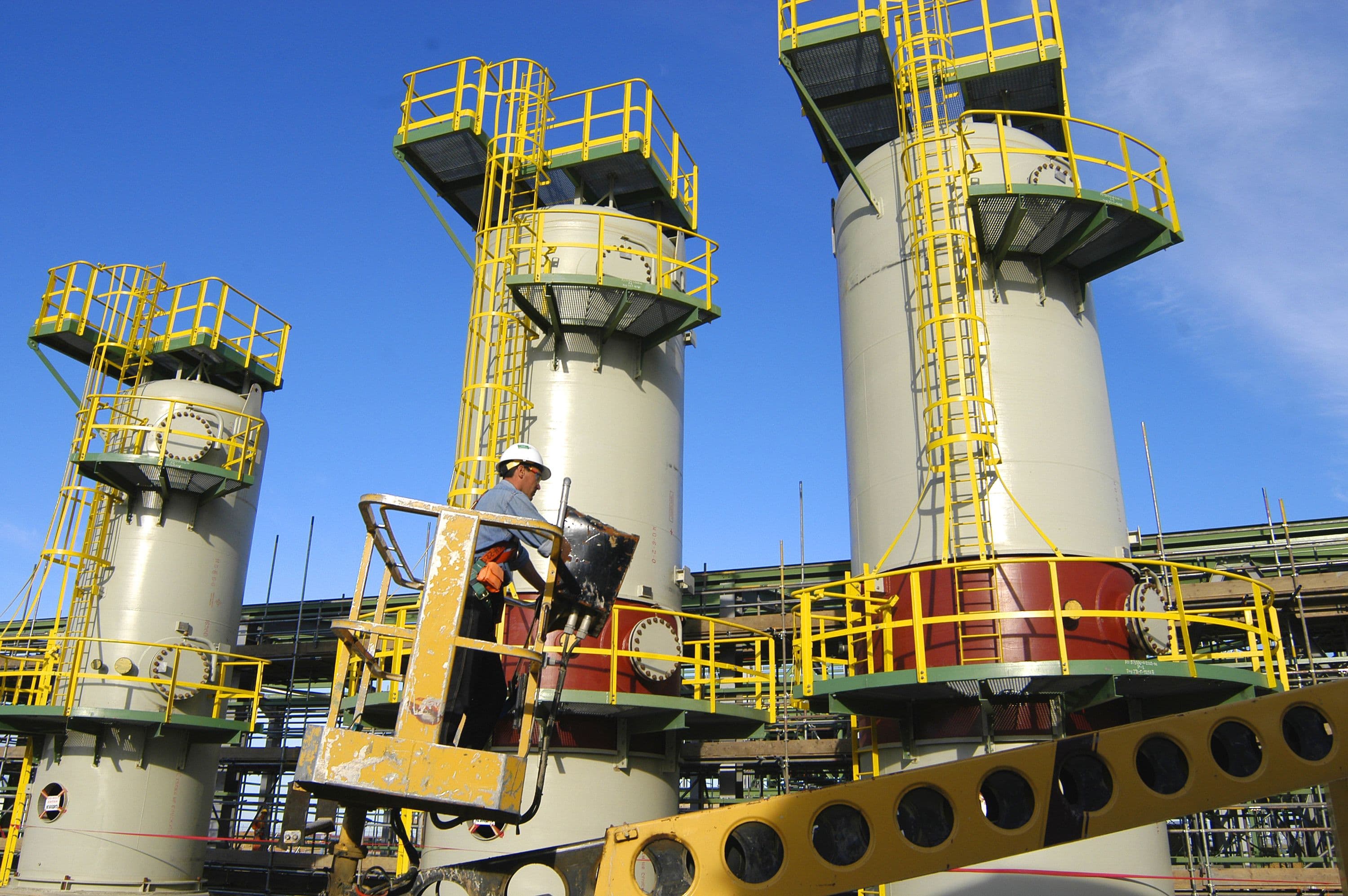 Worker on crane in front of pipe racks on vessels