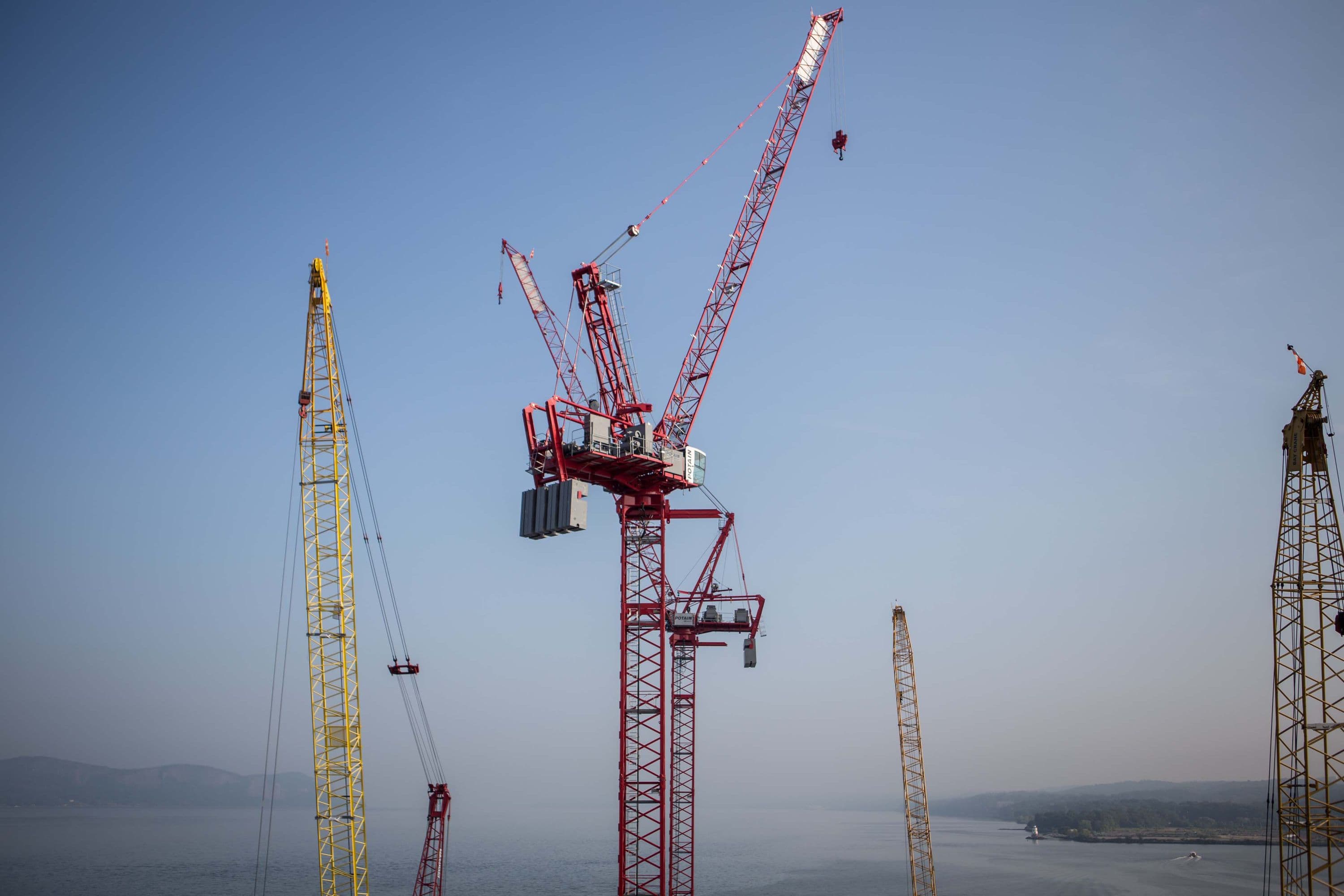 Tower cranes assist with the construction of the bridge's iconic towers.