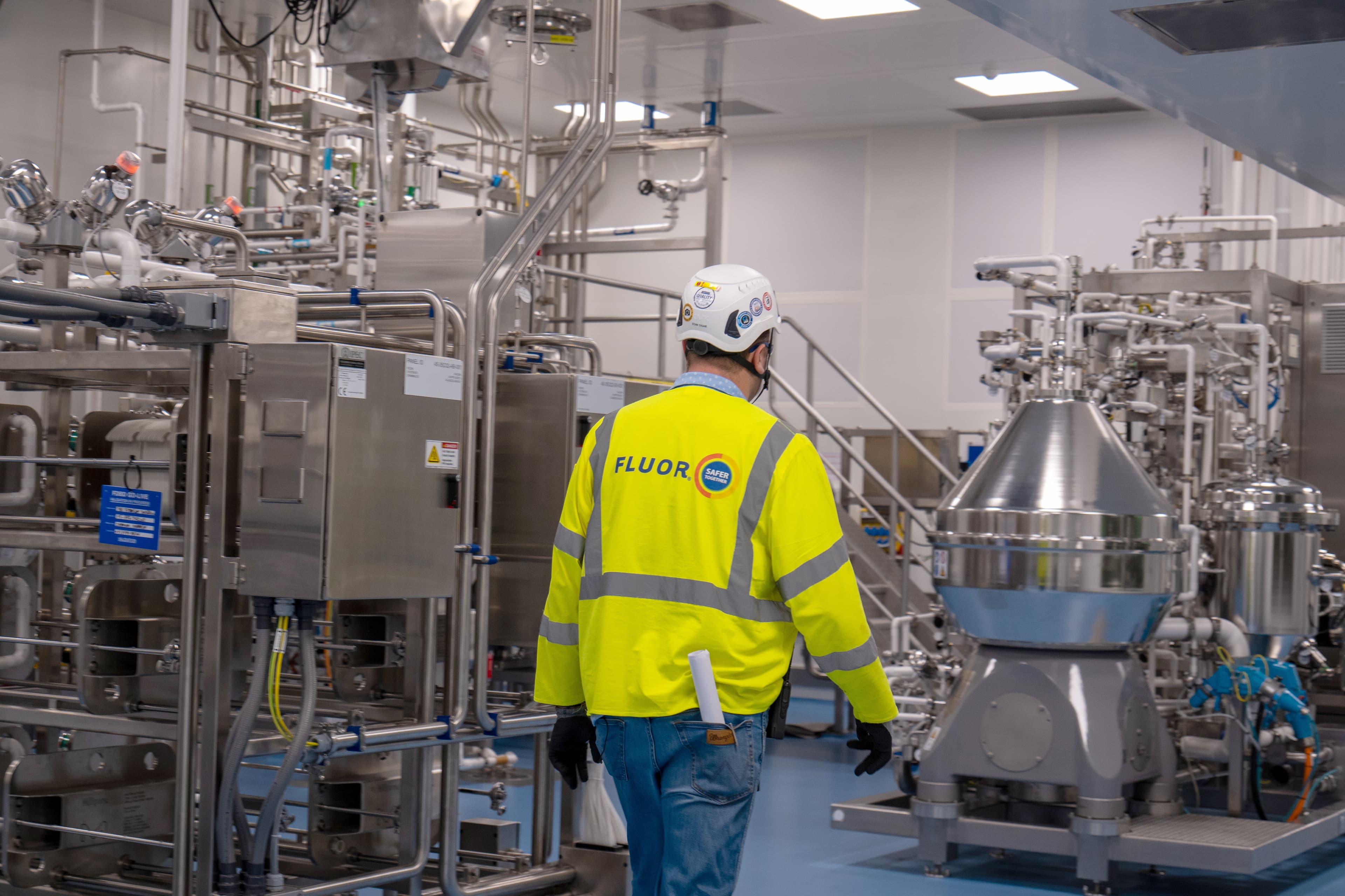 Worker in white hard hat and bright safety jacket in life sciences facility